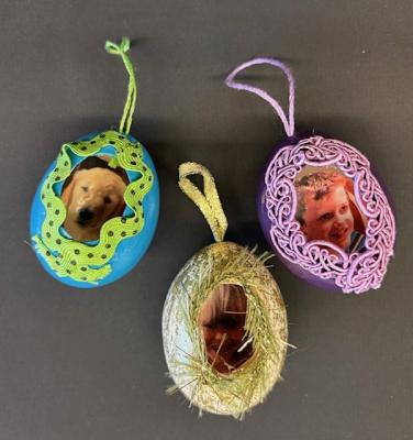 colorful empty eggs decorated on the inside with an image and trim and ribbon on the outside