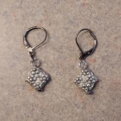 Square, silver with flower design earrings found in the Manor lower level laundry room.