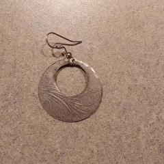 Earring: flat gold metal hoop with etching returned by Lyft driver.