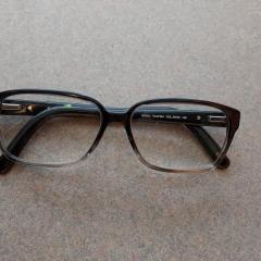 Black plastic reading glasses by FURLA found in the Manor Library.