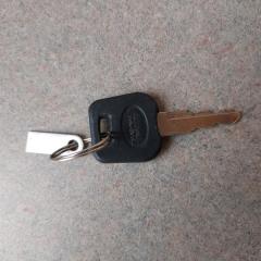 Small key with black top and metal tag found in the exercise room on the floor between elliptical and treadmill near the window.