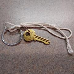 Gold mailbox key (on keyring with white string tied to it) found on the floor by the Manor mailboxes.