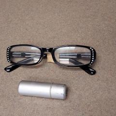 Black reading glasses with diamond accents and lipstick in silver case found in the fitness room.